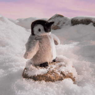Penguin cuddly toy on snow with mountains in the background