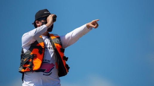 A researcher stood up, pointing out a river dolphin spotting out of frame