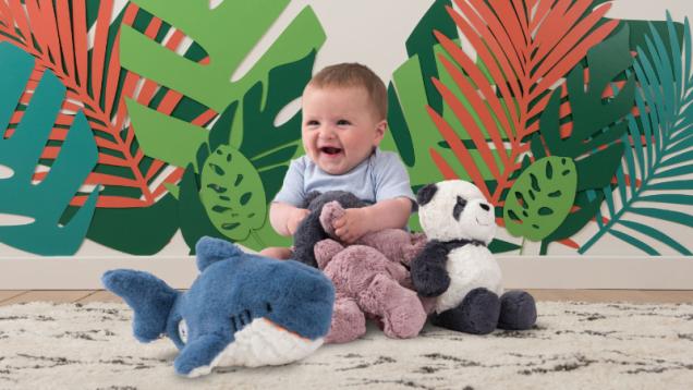 Baby sat with group of soft toys on colourful background