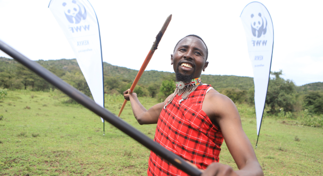 A Maasai man teases the camera as he wields a spear
