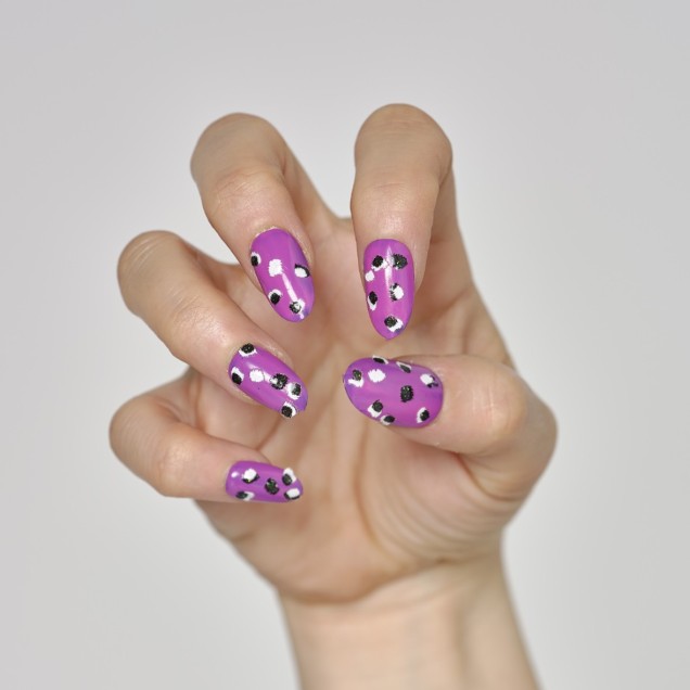 Fingernails painted purple with animal-print on them